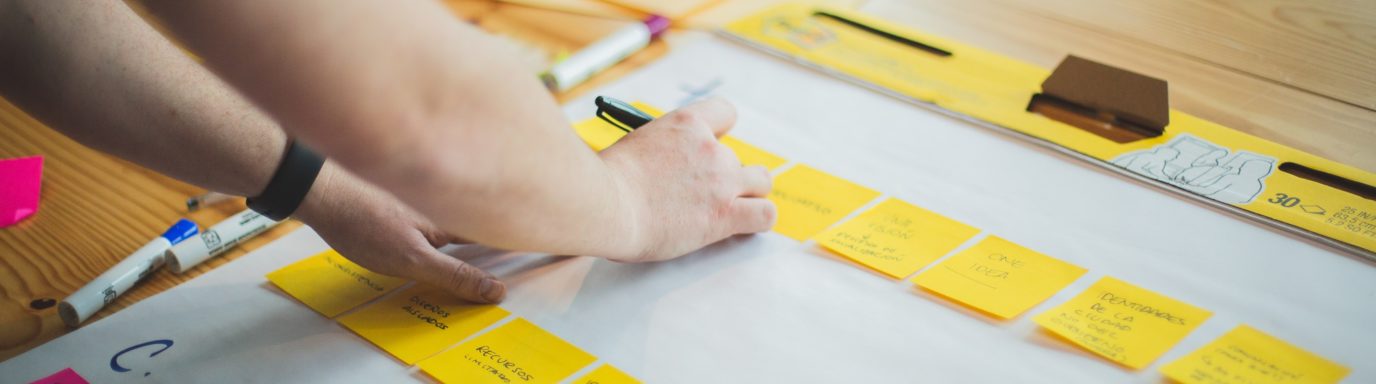 A desk with posit it notes and a person working through a workshop