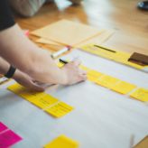 A desk with posit it notes and a person working through a workshop