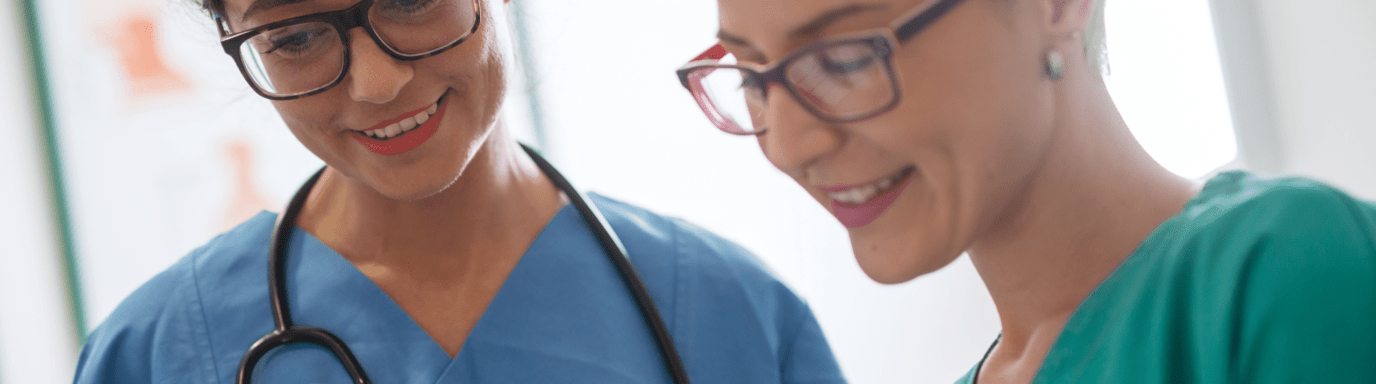 Two female medical professionals looking at paperwork and smiling