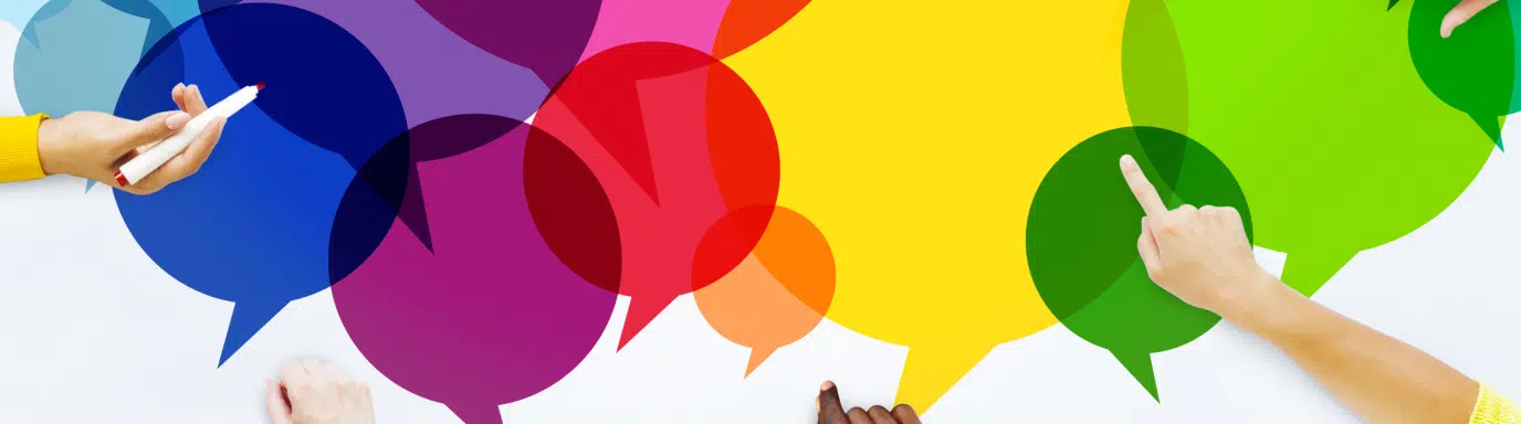 A group of people sat around a table with coffees, a series of colourful speech bubbles in the middle of the table