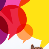 A group of people sat around a table with coffees, a series of colourful speech bubbles in the middle of the table