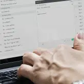A woman typing notes on her laptop at her desk