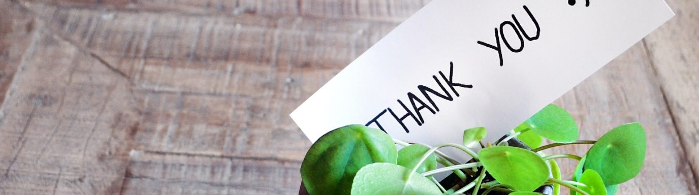 A plant pot on a table with a note that says -thank you