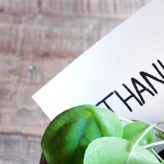 A plant pot on a table with a note that says -thank you