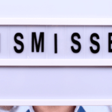 A man holding up a lightbox with the word 'dismissed' on