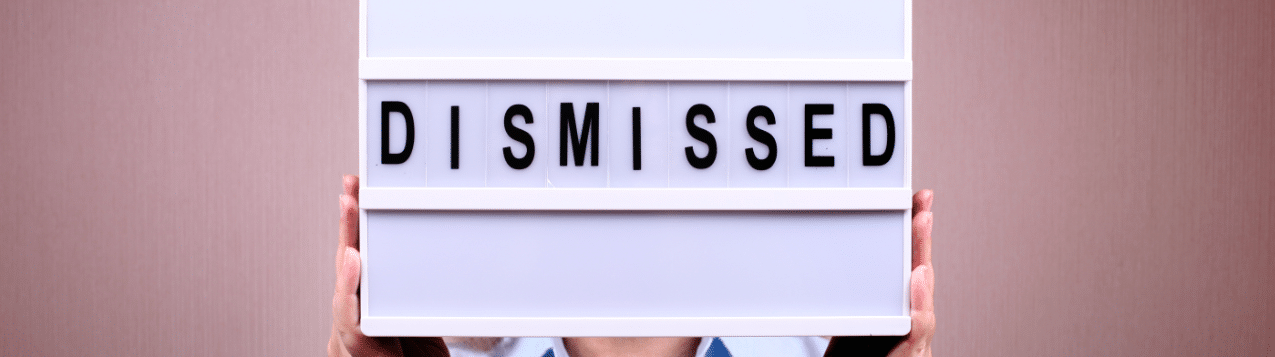 A man holding up a lightbox with the word 'dismissed' on