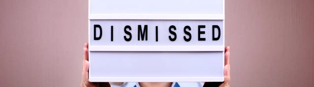 A man holding up a lightbox with the word 'dismissed' on