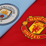 Manchester United and Manchester City football club badges next to each other