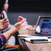 A man using his hands to talk to his colleague sat at a desk