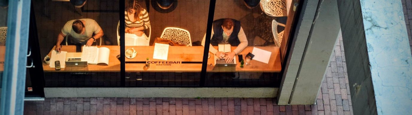 People sat at a coffee bar working on their laptops