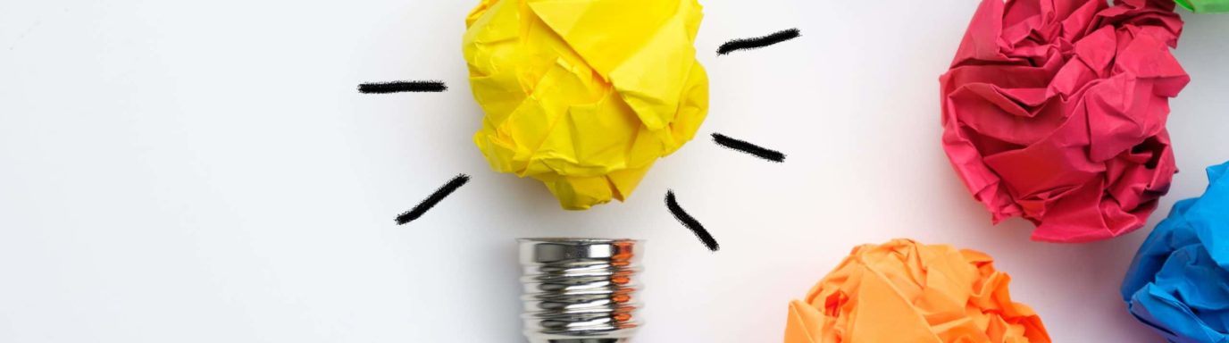 A lightbulb made from scrunched up yellow paper, with other coloured paper surrounding