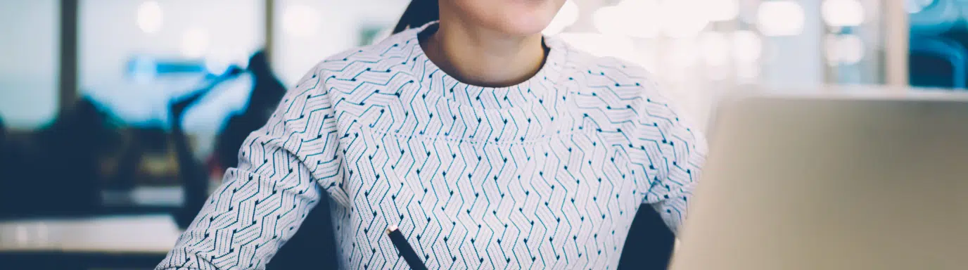 Woman making notes whilst attending a training course on her laptop