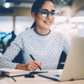 Woman making notes whilst attending a training course on her laptop
