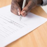 Person writing on a piece of paper using a fountain pen