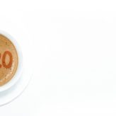 A full coffee cup with 2020 written in the coffee on a white background