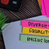 Pink, yellow and green post it notes with the words diversity, equality and inclusion hand-written on them