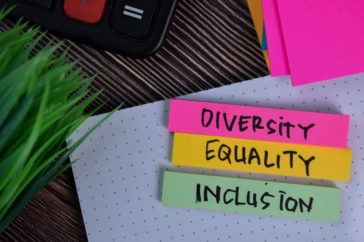 Pink, yellow and green post it notes with the words diversity, equality and inclusion hand-written on them