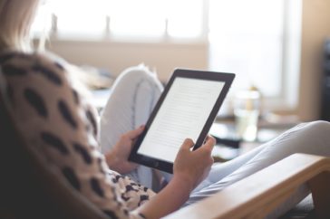An employee reading work notes on her ipad in her living room