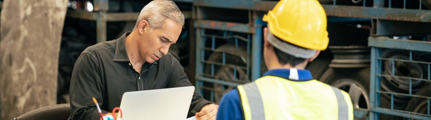 A manager sitting at a desk interviewing an employee wearing PPE equipment