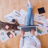 An employee sat on the floor working with her cat laying beside her