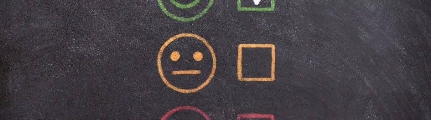 A blackboard with smiley face rating system - sad face to happy face