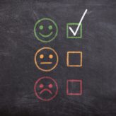 A blackboard with smiley face rating system - sad face to happy face