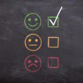 A blackboard with smiley face rating system - sad face to happy face