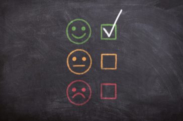 A blackboard with smiley face rating system - sad face to happy face