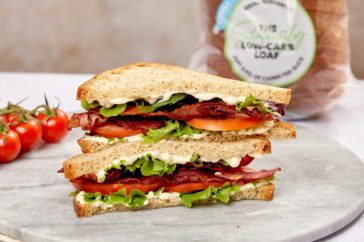 A double-stacked sandwich on a plate containing bacon, lettuce and tomato