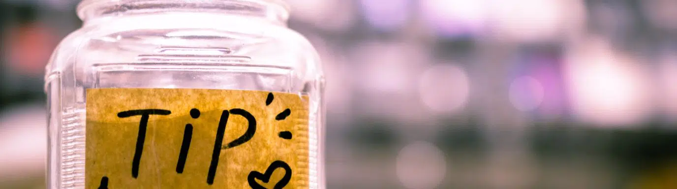 A single jar filled with cash with a label reading 'Tip'