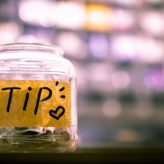A single jar filled with cash with a label reading 'Tip'