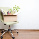 A chair with a box full of office equipment on top of it