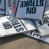 A pile of signs on the floor that say 'on strike'